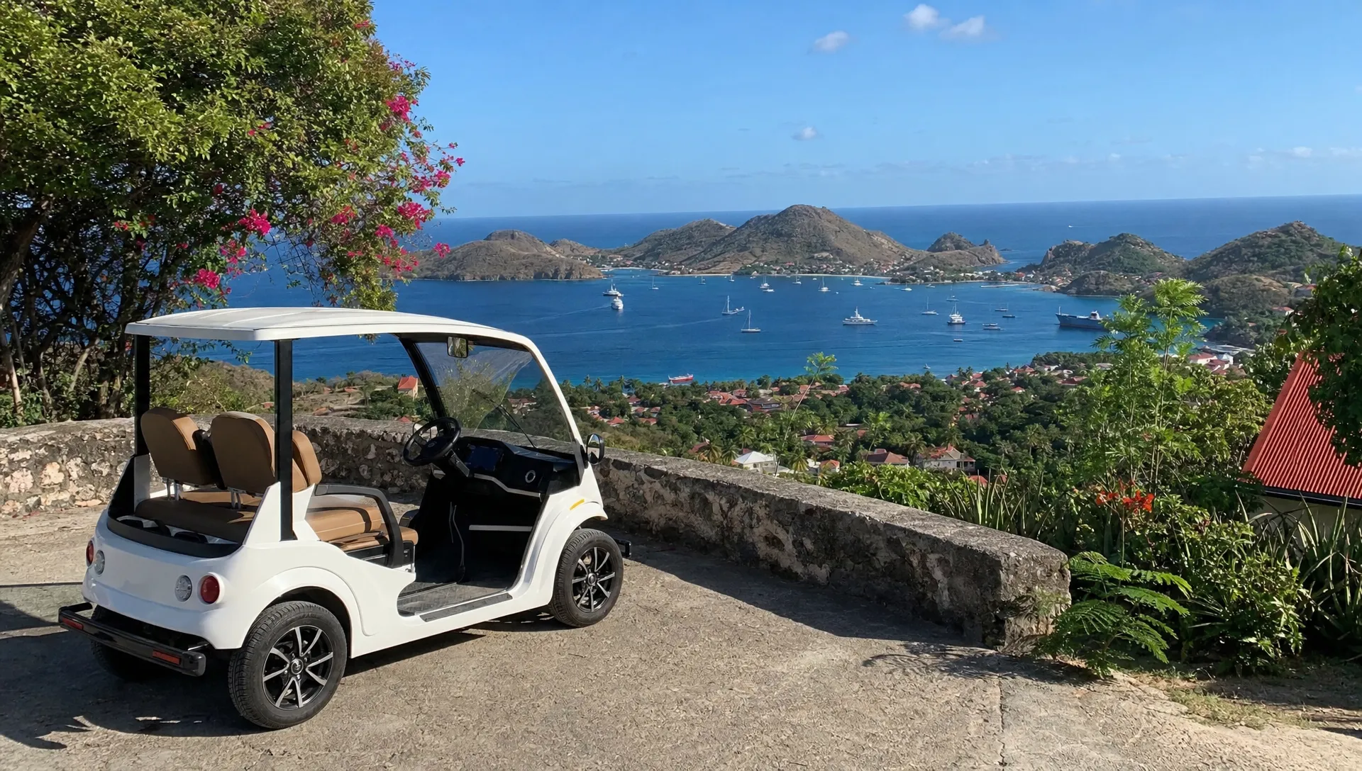 Une voiturette électrique garée au bord d’un belvédère à Terre-de-Haut, avec la baie des Saintes en arrière-plan, quelques maisons colorées plus bas et une végétation tropicale tout autour du point de vue.