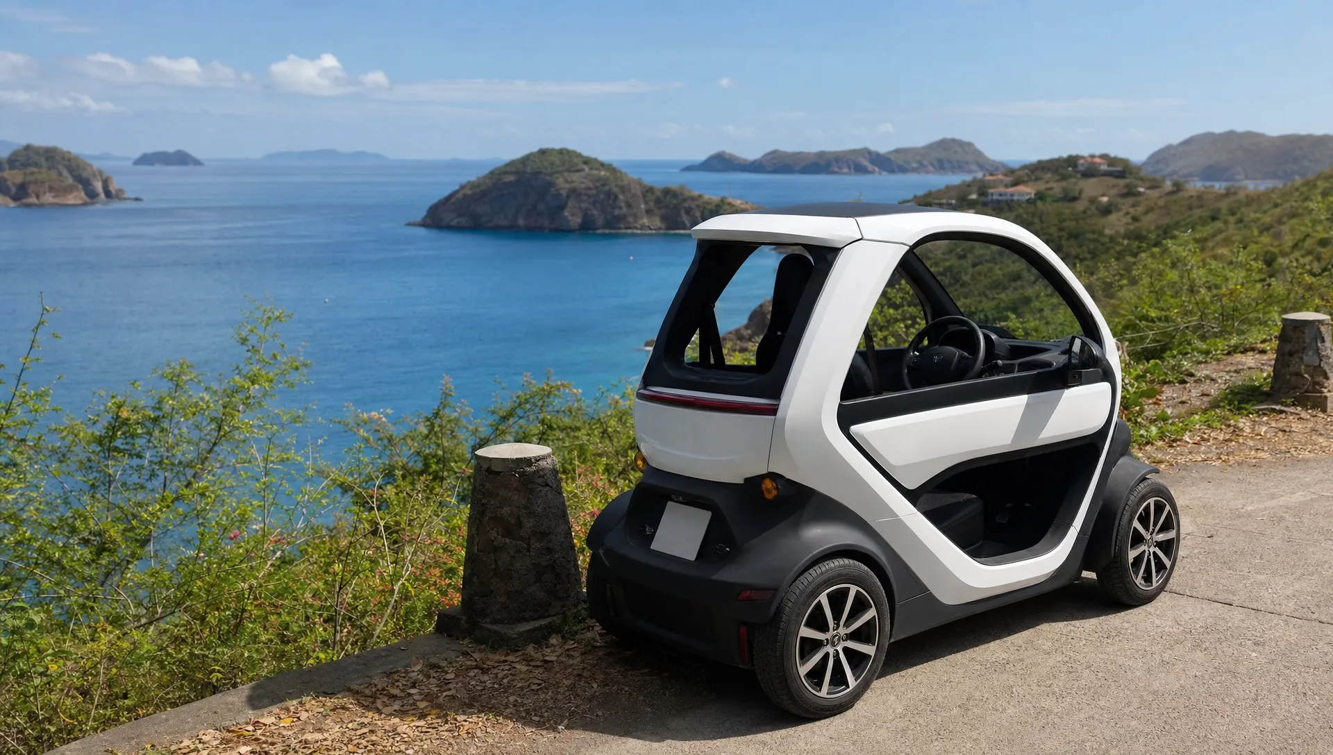 Une voiturette électrique compacte est stationnée près d’un chemin côtier aux Saintes, avec deux places visibles et la mer en arrière-plan pour des trajets courts sur l’île.
